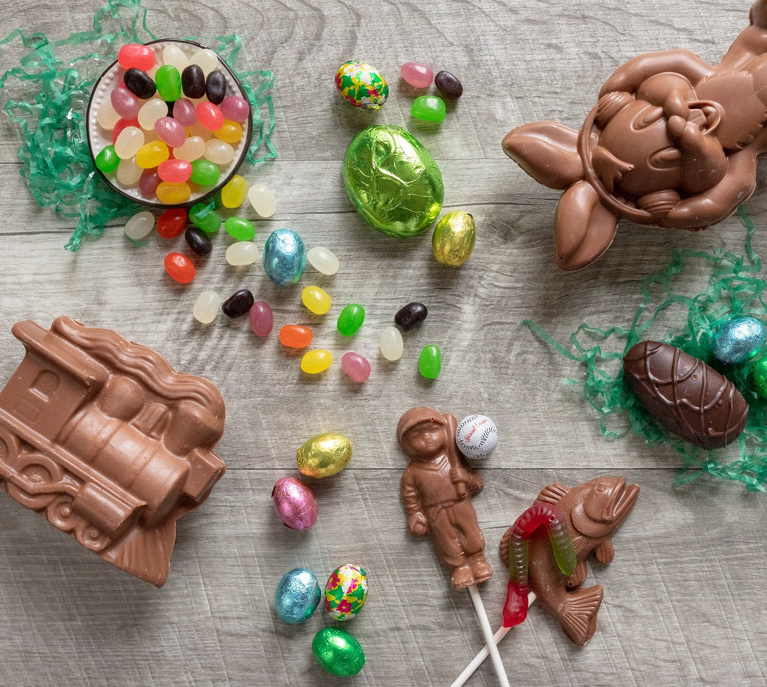 A chocolate train, a baseball player sucker with foil baseball, bunny wearing earbuds, cream egg, marshmallow egg, foiled eggs, and jelly beans 